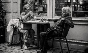 two women out side a cafe sitting at a table having a drink